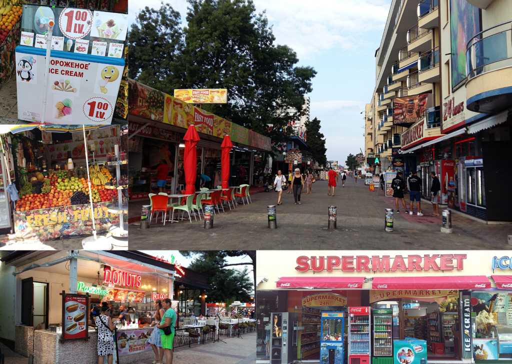 Pedestrians walk along a Sunny Beach street lined with shops and food stalls
