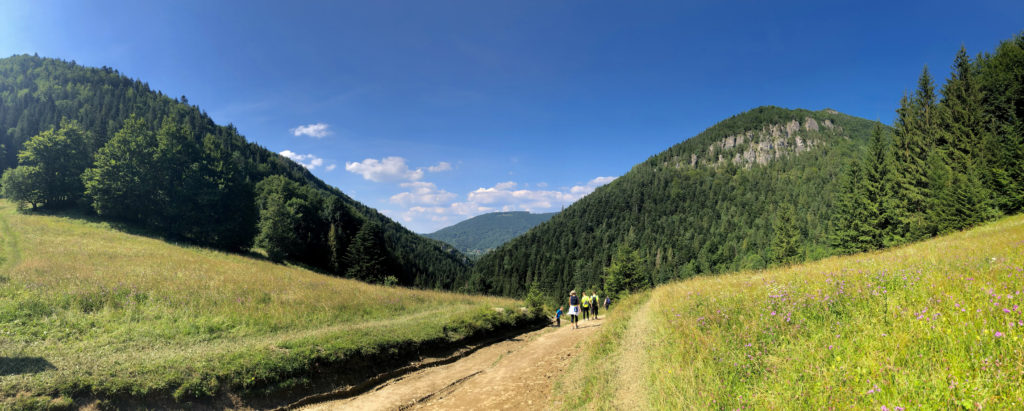 Hikers walk along a dirt path through the scenic Jánošík’s Lower Holes valley