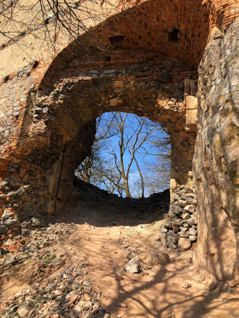 Brick archway of a ruined castle looking out toward bare trees