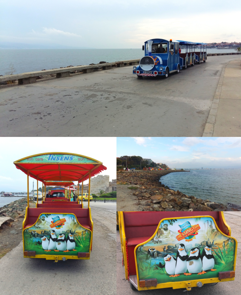 A blue tourist train drives along the waterfront in Nessebar, Bulgaria