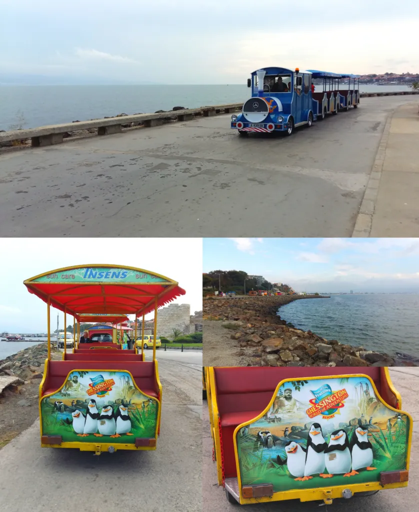 A blue tourist train drives along the waterfront in Nessebar, Bulgaria