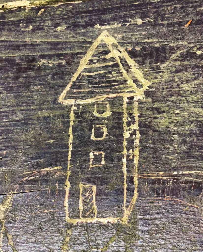 Simple house outline carved into a dark wooden surface
