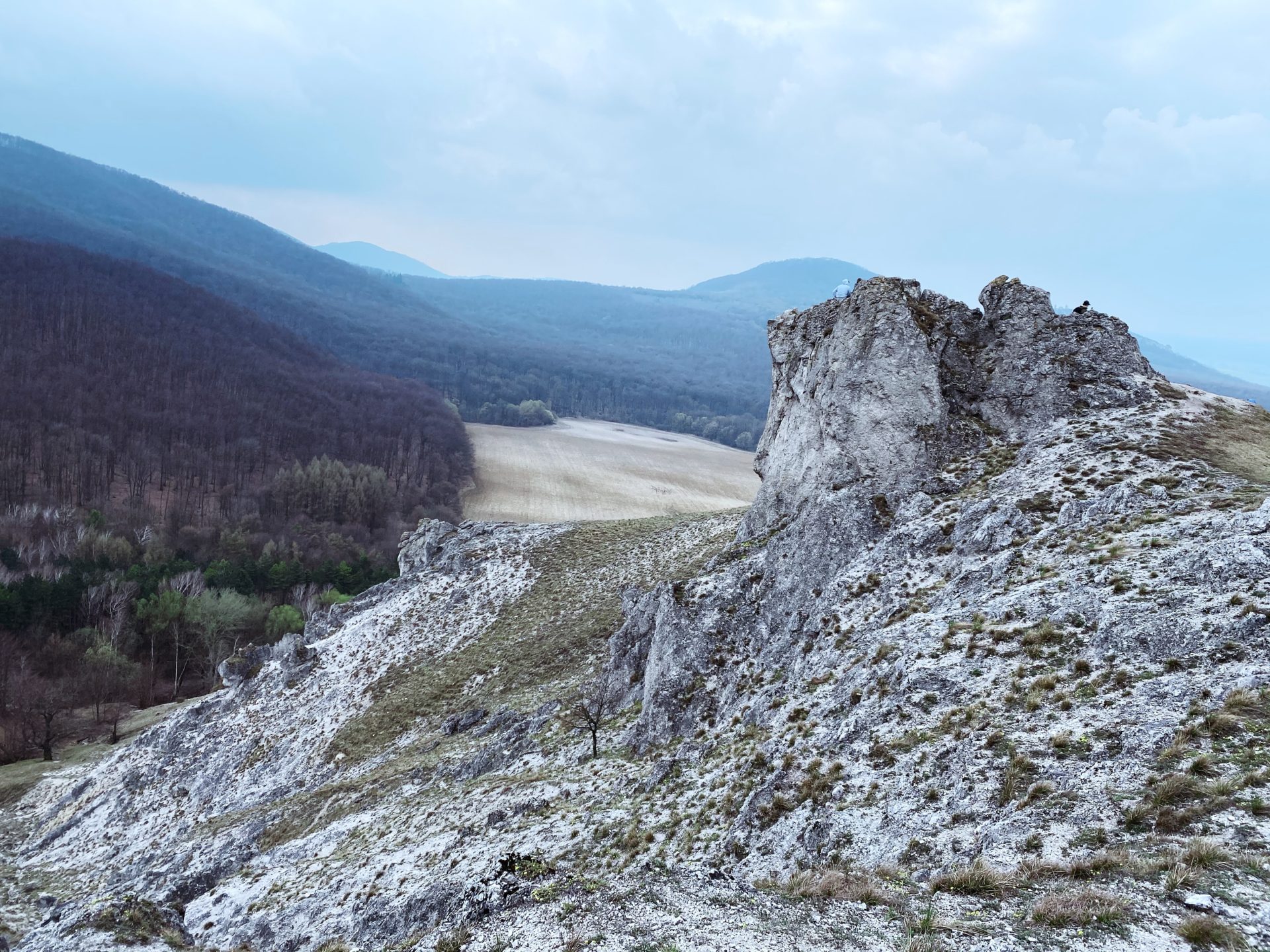 Rugged limestone cliffs overlook a valley and forested hills in Plavecký Mikuláš
