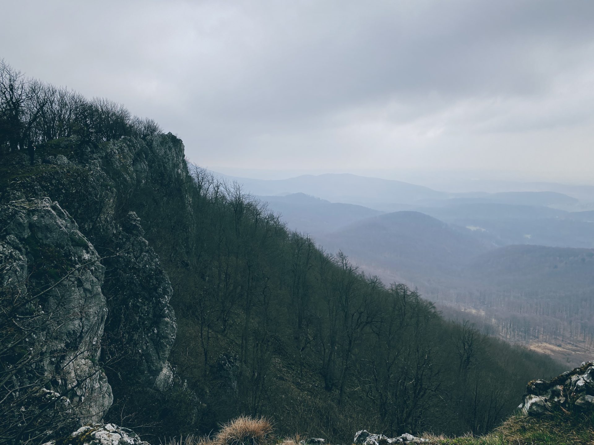Rocky cliffs overlook a forested valley under a cloudy sky in Plavecký Mikuláš