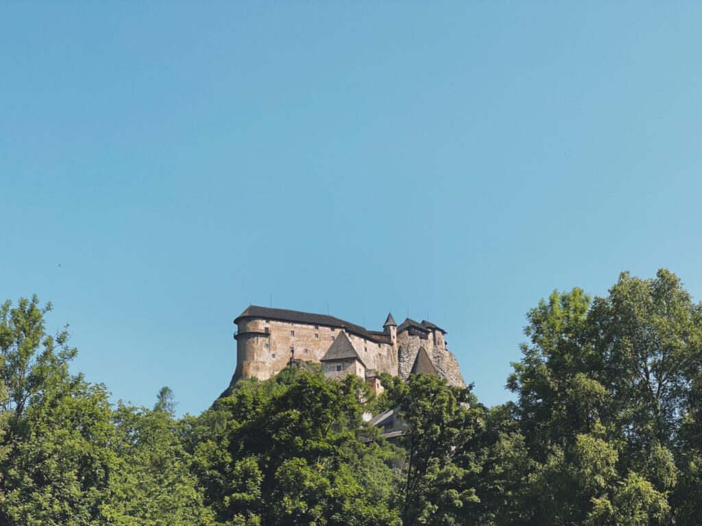 Orava Castle perched on a rocky cliff above lush green trees