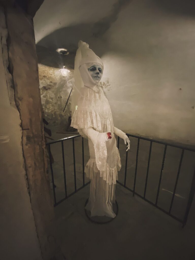 A mannequin in a white lace dress stands on display inside Orava Castle