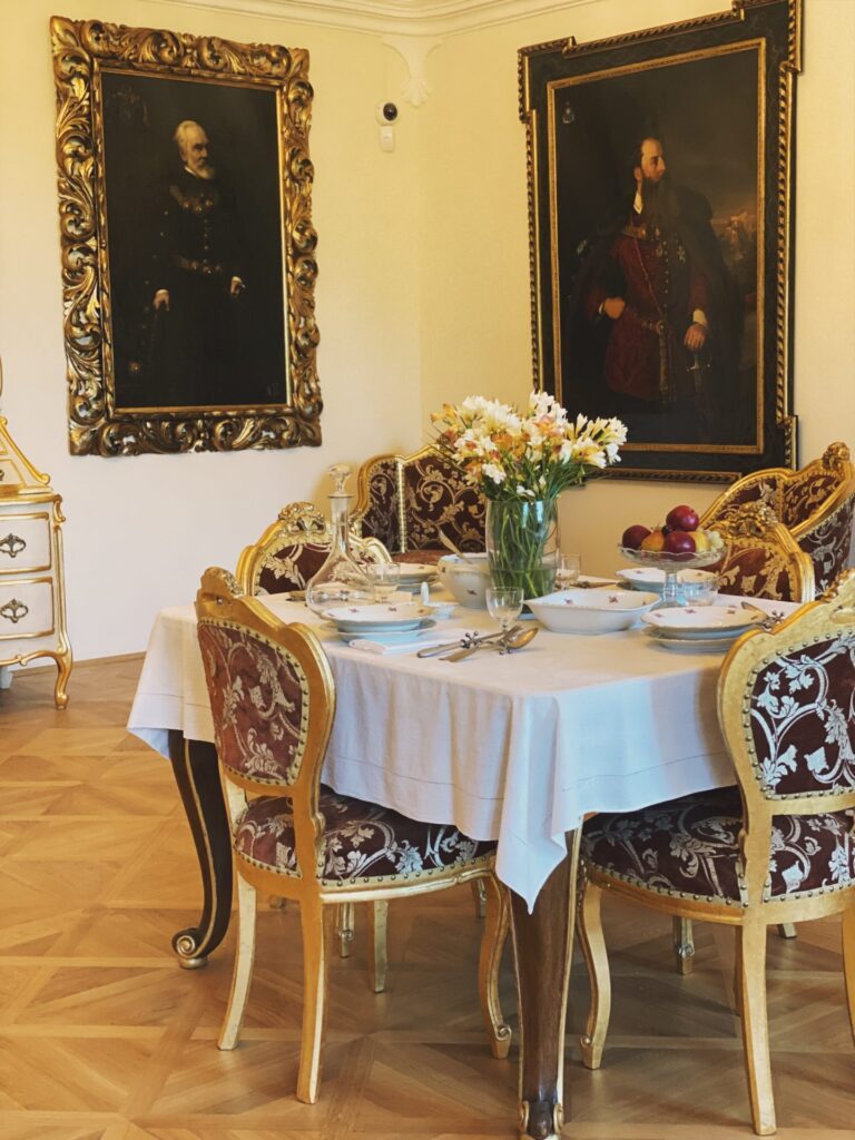 Ornate chairs surround a dining table set for a meal at Orava Castle