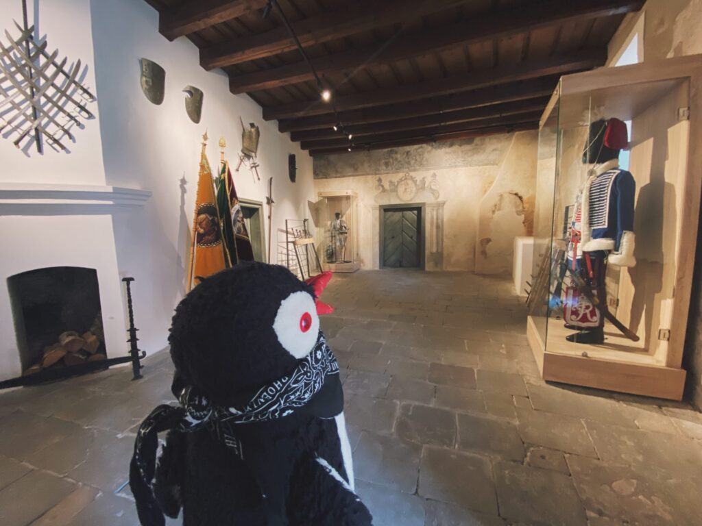 A plush penguin toy stands inside a historic room at Orava Castle