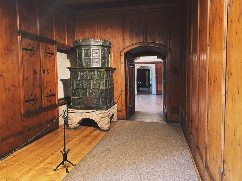 Ornate green tiled stove inside a wood paneled room at Orava Castle