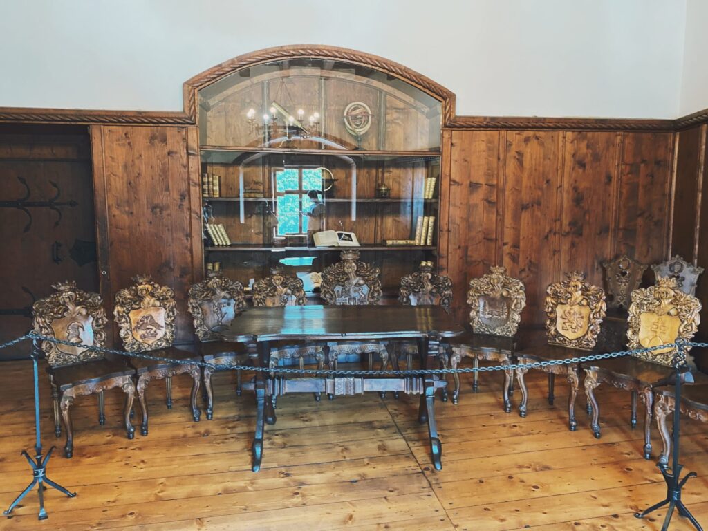 Ornate wooden chairs surround a table inside a room at Orava Castle