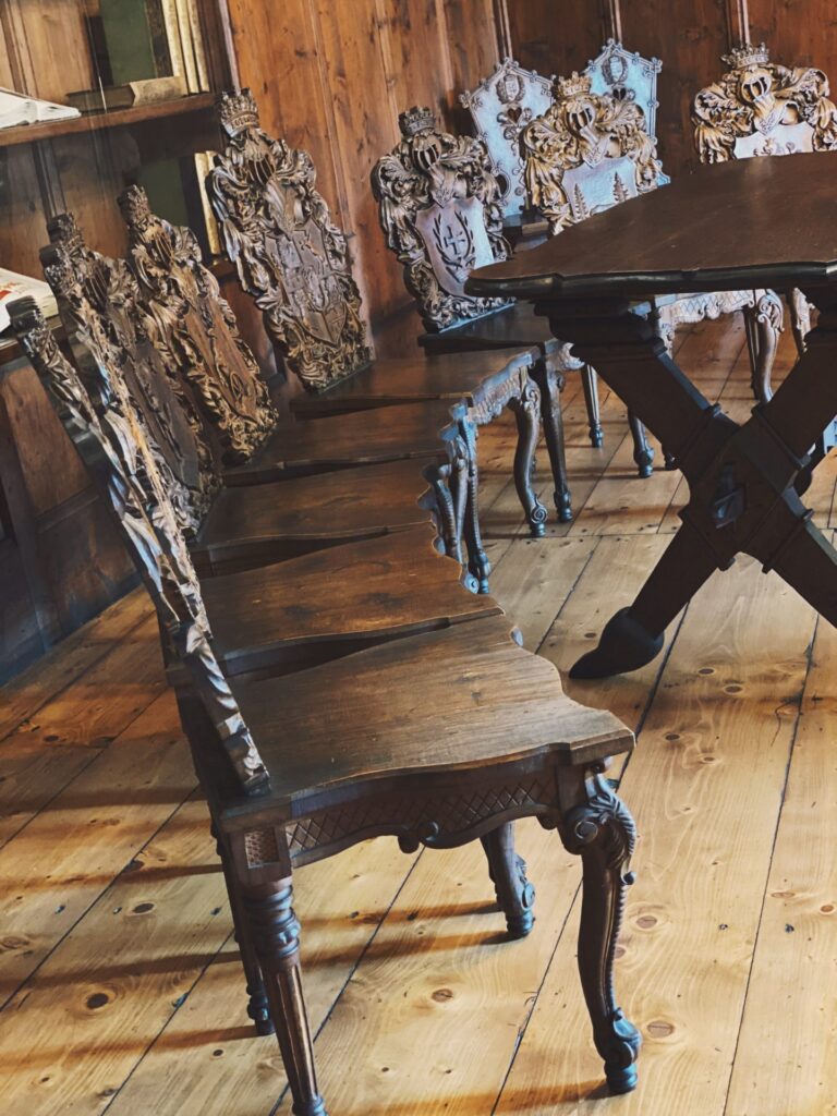 Ornate wooden chairs with carved crests arranged around a table at Orava Castle