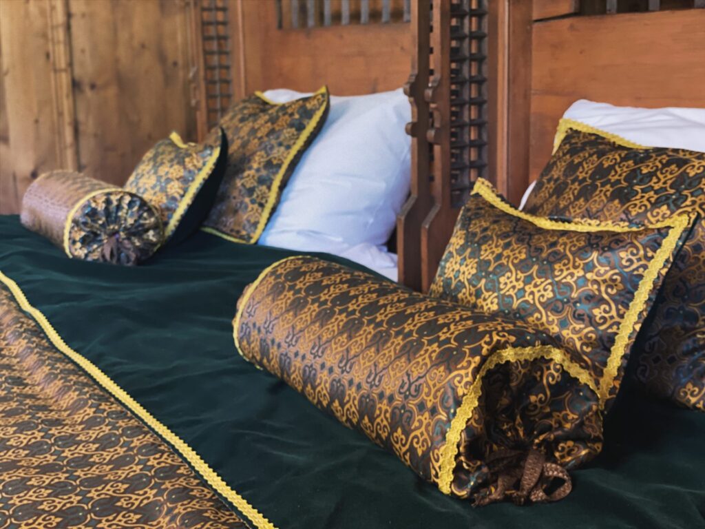 Ornate pillows and bolsters rest on a bed inside Orava Castle
