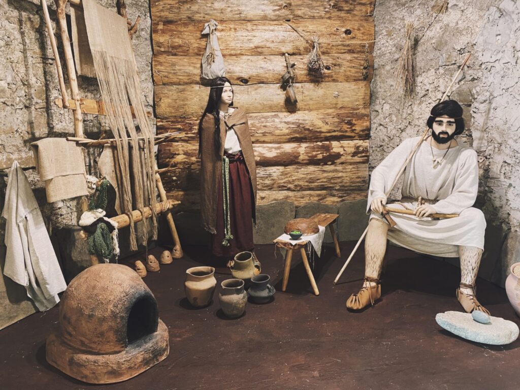 Mannequins dressed in historical clothing stand inside a rustic Orava Castle room exhibit