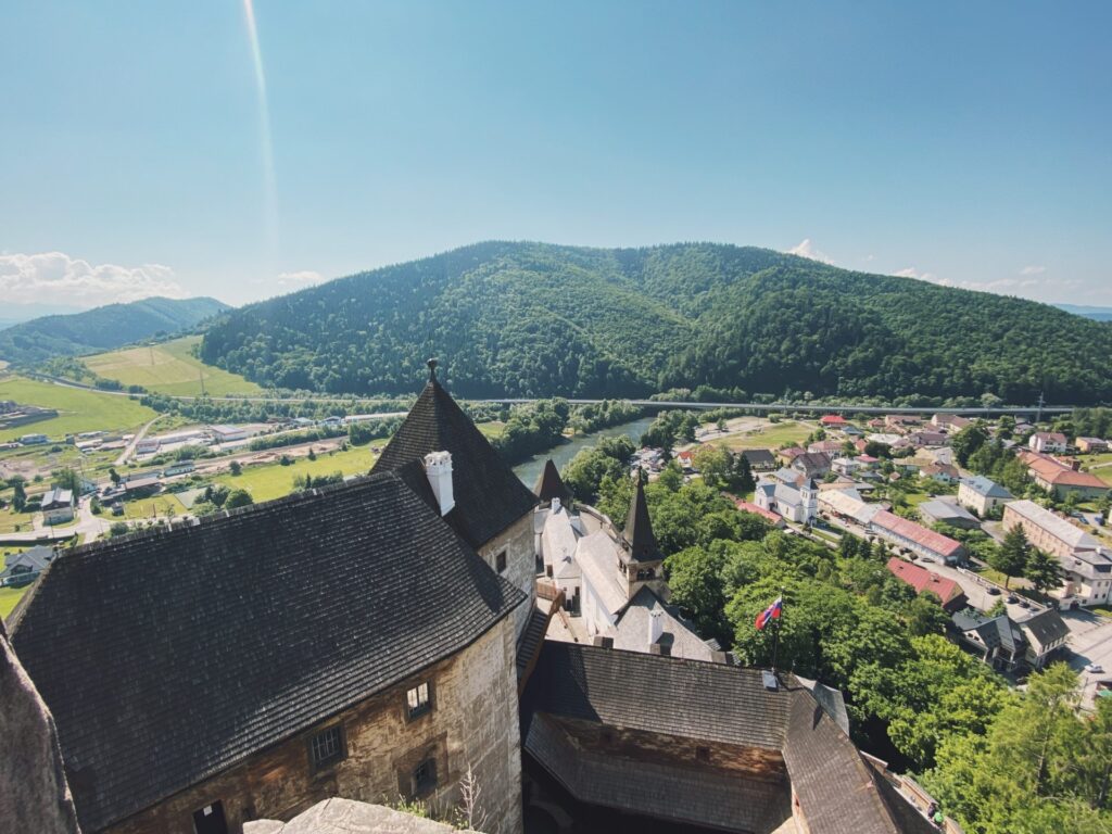 High angle view of Orava Castle overlooking a lush valley and village