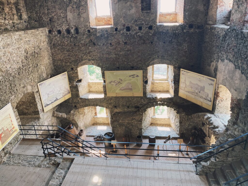 Informational posters and maps hang on the stone walls inside Stará Ľubovňa Castle
