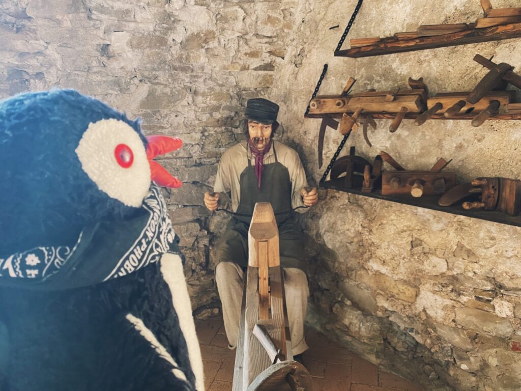 A plush penguin toy faces a mannequin craftsman inside Stará Ľubovňa Castle