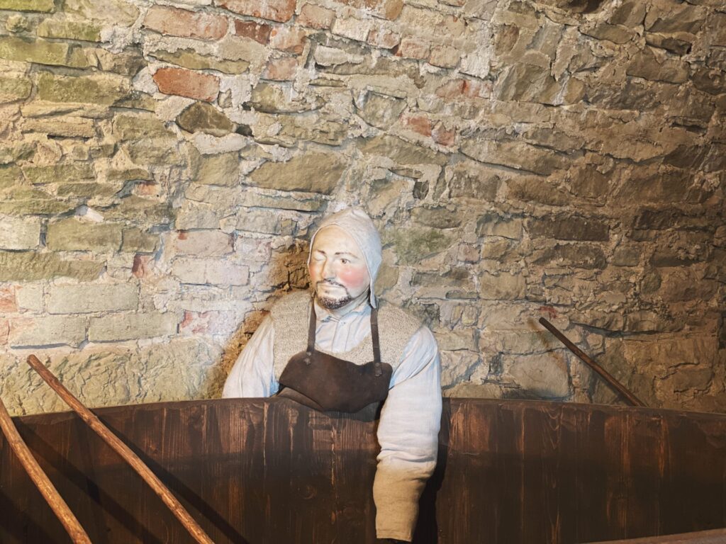 A mannequin dressed as a historical worker stands before a stone wall