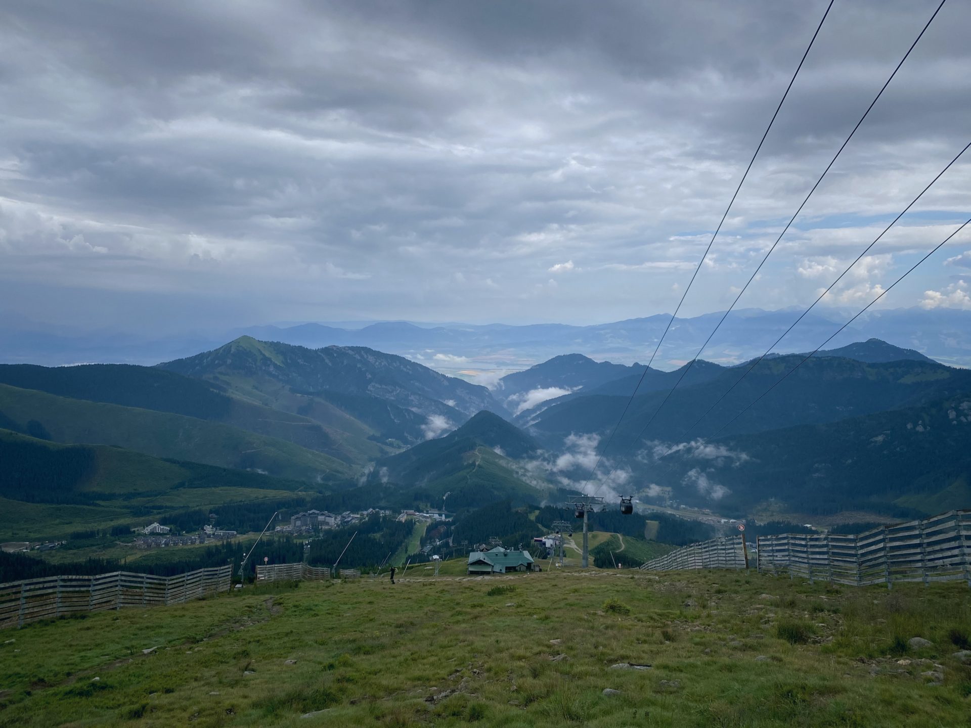 Cable cars descend over a valley in the Low Tatras under cloudy skies