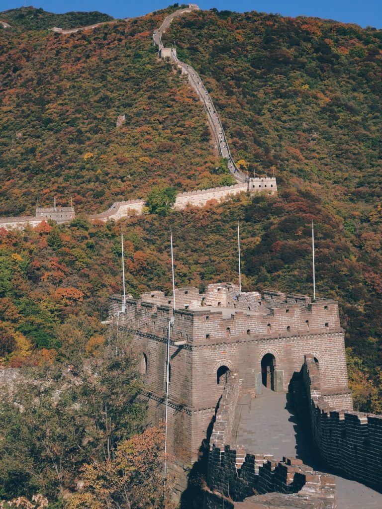 The Great Wall of China winds through mountains covered in autumn foliage