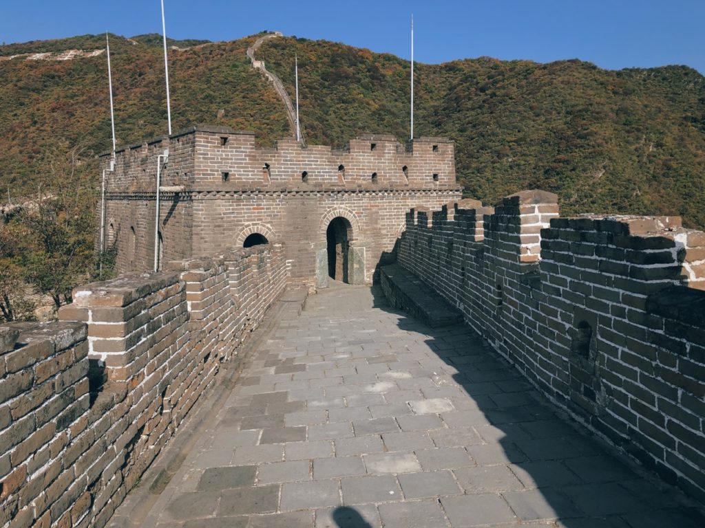 Stone watchtower and walkway along the Great Wall of China under blue sky