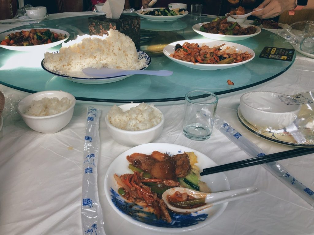 Various Chinese dishes and bowls of rice served on a rotating glass table