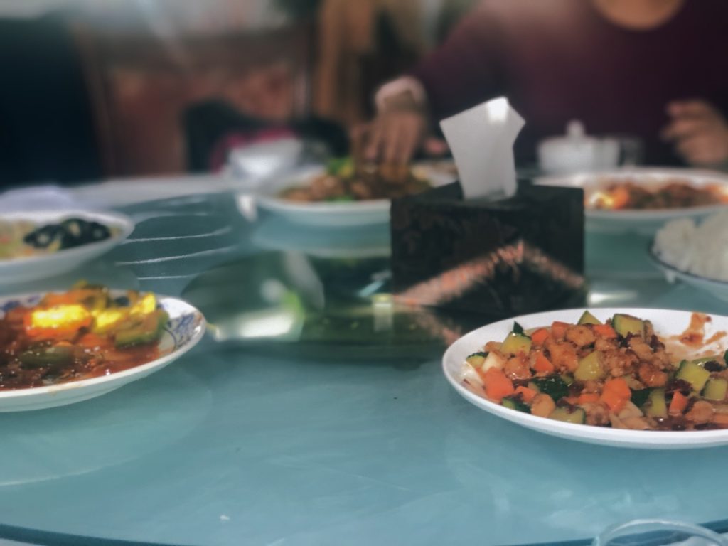 Several plates of stir-fried vegetables and meat on a round table