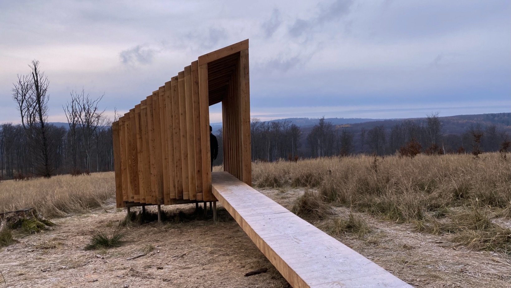 Wooden structure at the Vydrica Observatory overlooking a field and distant forest