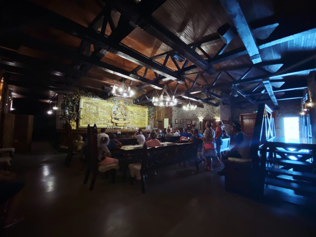 People sit at tables inside the rustic, wood-beamed Nestville Whiskey distillery hall
