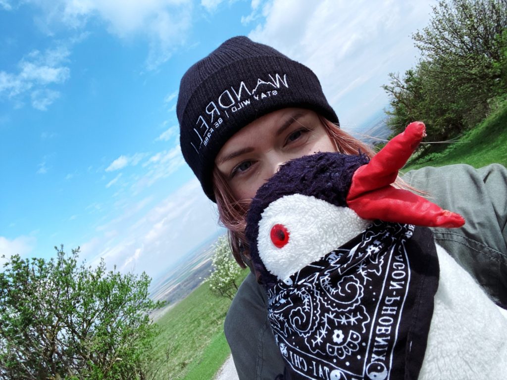 Plush penguin mascot Miško held by a person on Braunsberg Hill