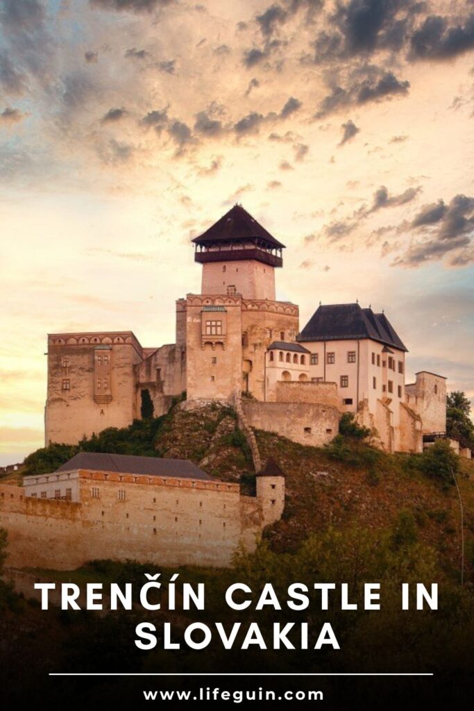 Trenčín Castle stands on a rocky hill under a dramatic sunset sky