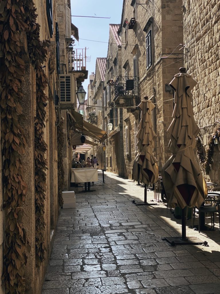Narrow stone alleyway with closed umbrellas in Dubrovnik old town