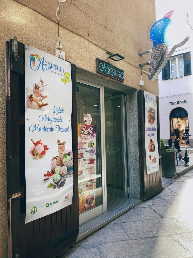 Storefront of Azzurra ice cream shop with colorful advertisements on a narrow street