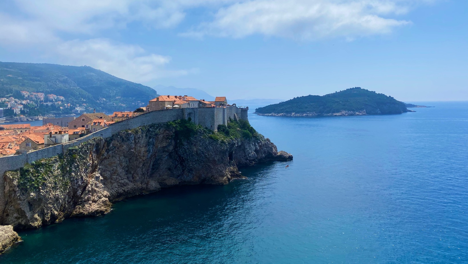 The historic city walls of Dubrovnik on a cliff overlooking the blue sea