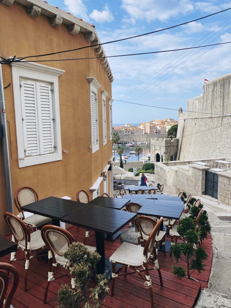 Outdoor dining tables on a terrace overlooking the harbor in Dubrovnik