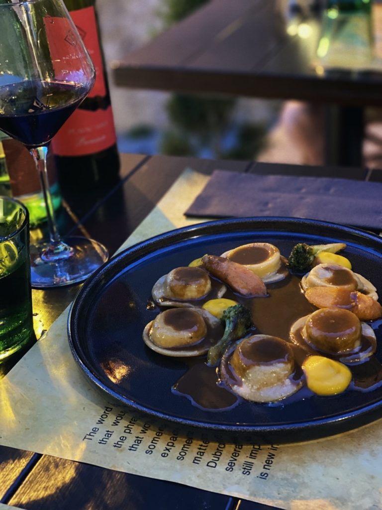Plated ravioli with sauce and vegetables served with red wine in Dubrovnik