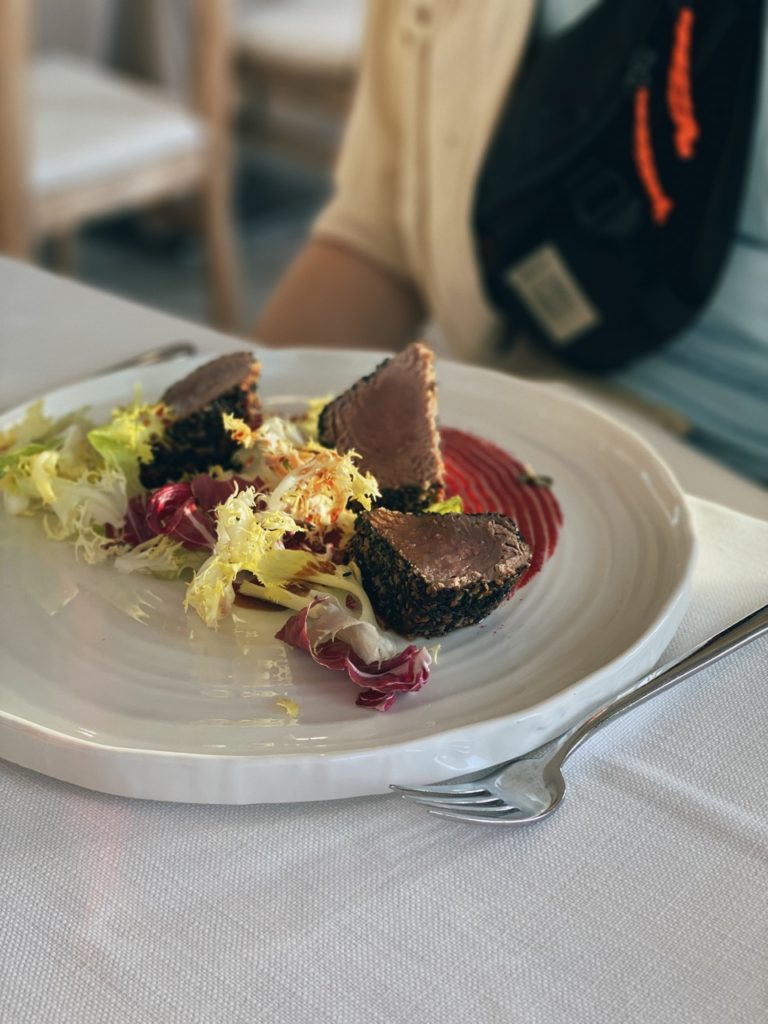 Seared tuna crusted with seeds served with fresh salad on a white plate