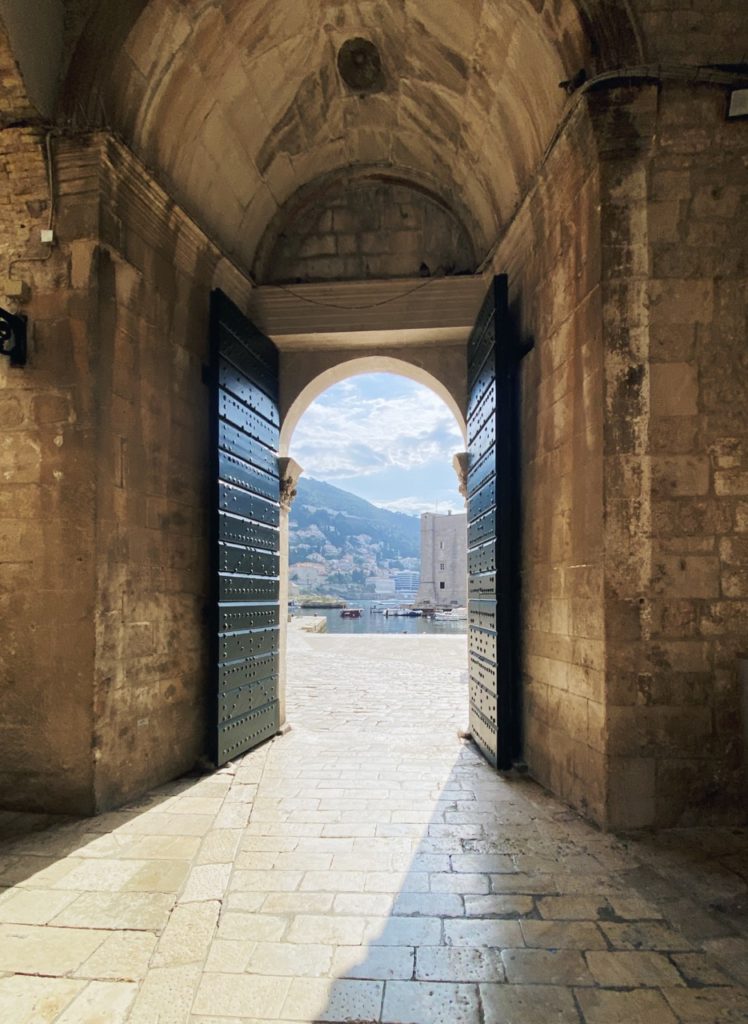 Stone gateway with large open doors in Dubrovnik looking out toward the harbor