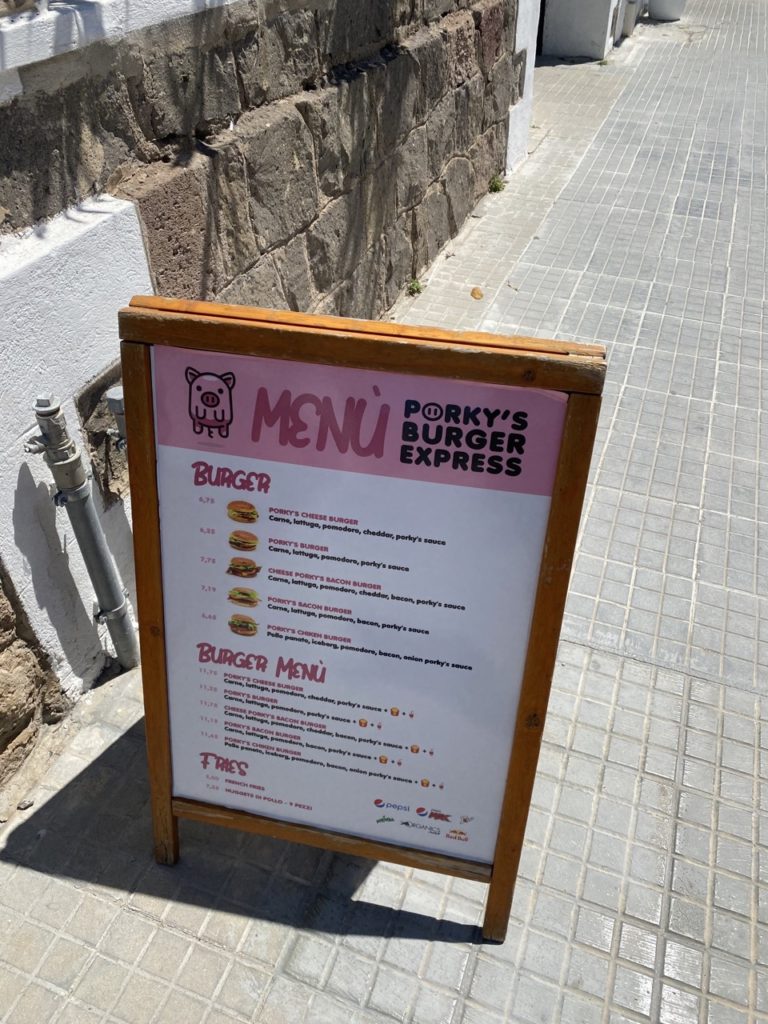 A wooden sandwich board menu for Porky's Burger Express on a sidewalk