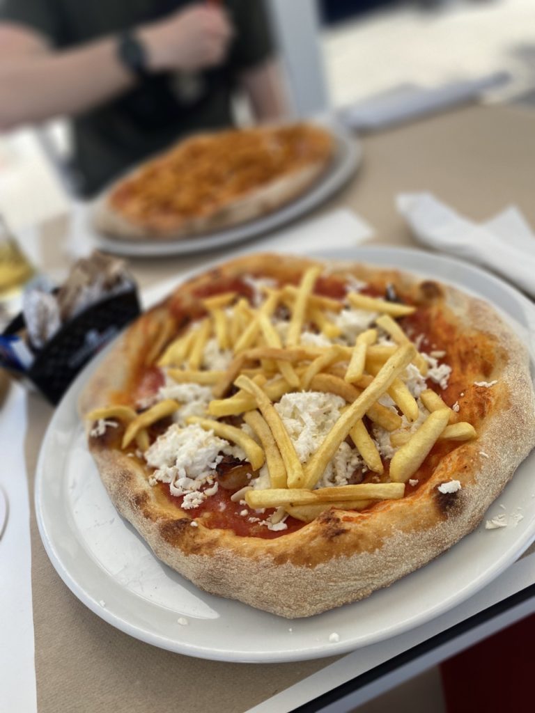 Pizza topped with french fries and white cheese on a restaurant table