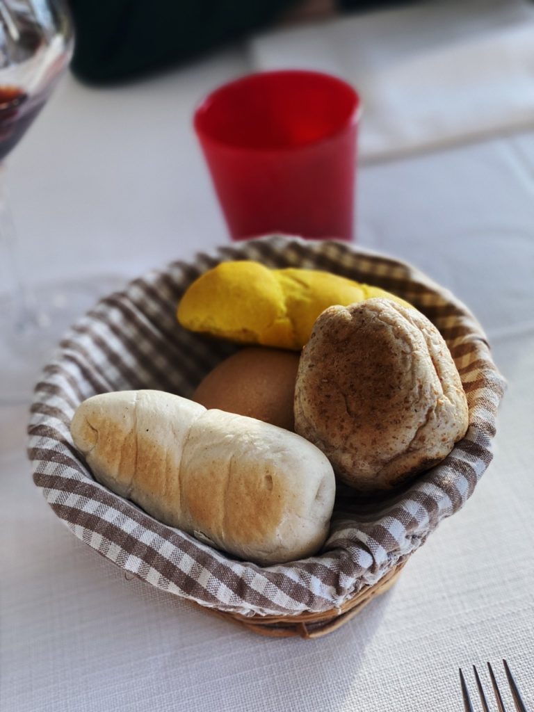 Assorted bread rolls in a checkered cloth basket on a restaurant table