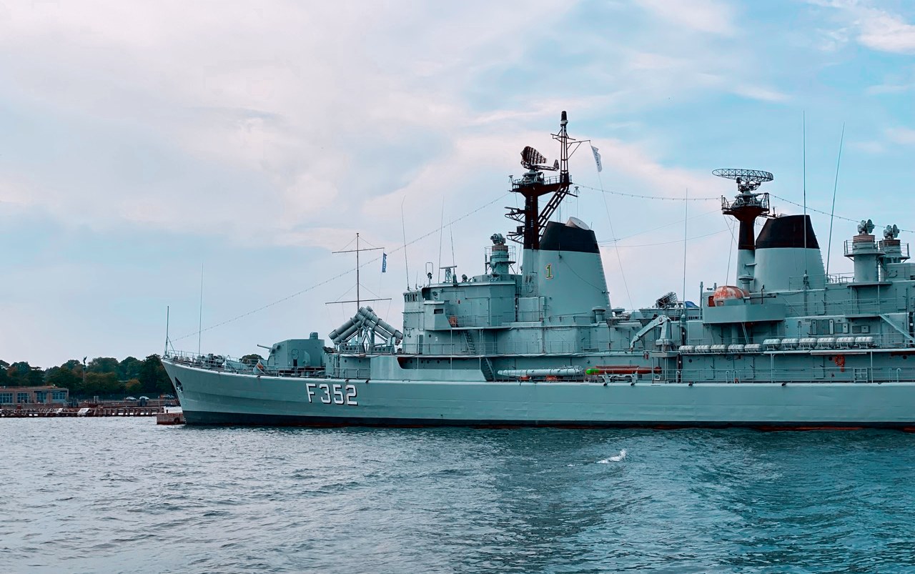 A grey naval frigate moored in Copenhagen harbour