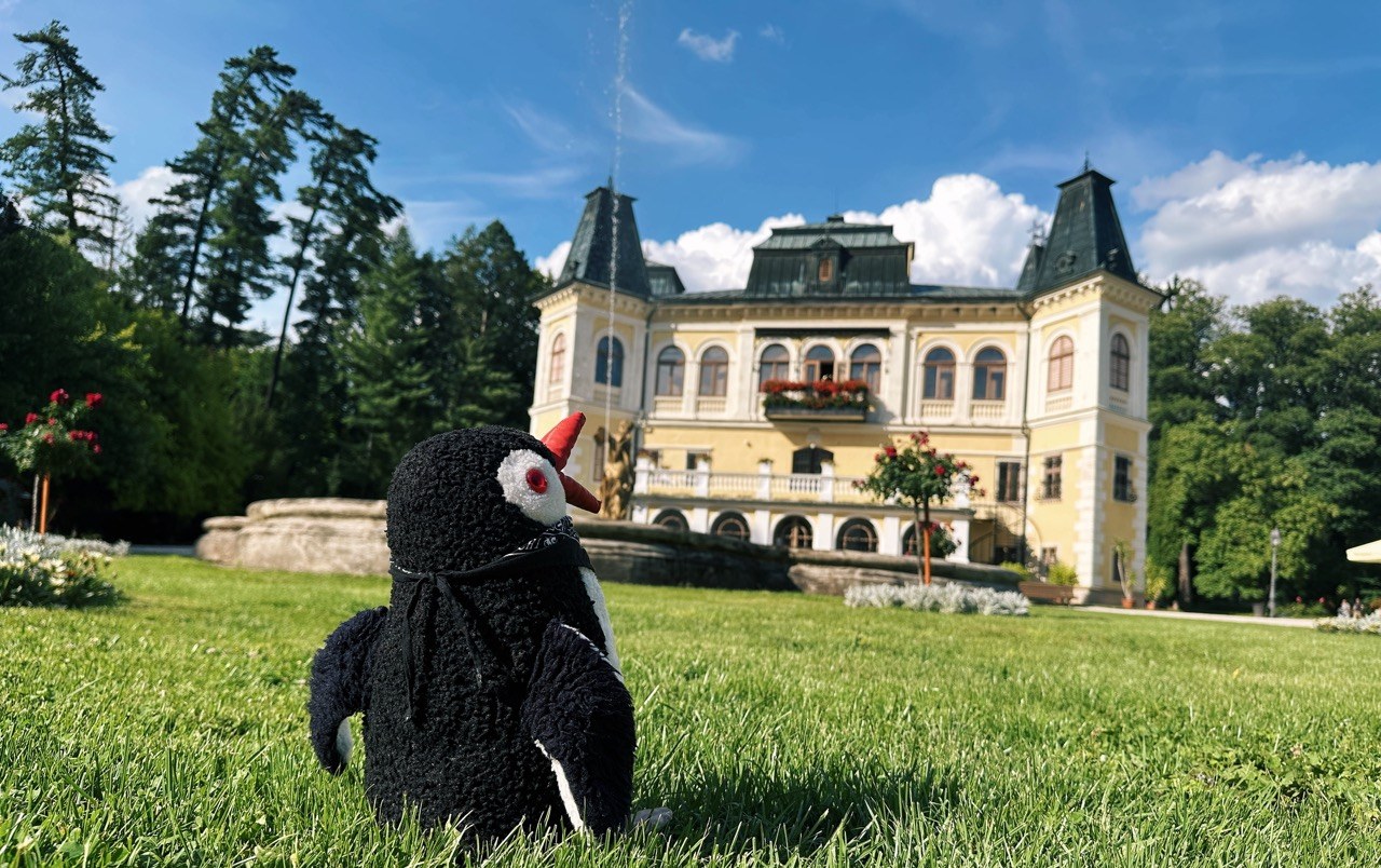 Miško the toy penguin on the lawn in front of Château Betliar, Slovakia