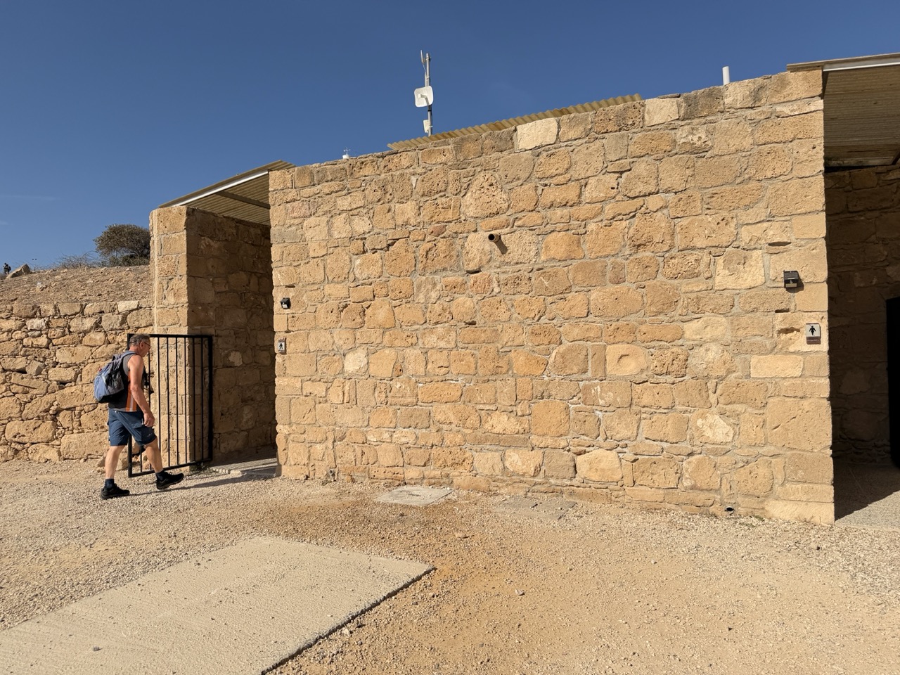 A hiker walks past a stone building at Paphos Archaeological Park