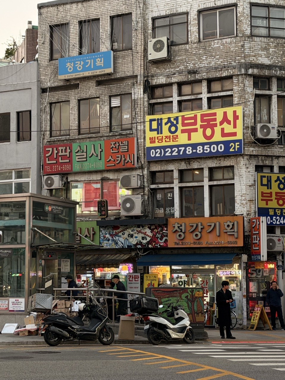 Street view of a weathered Seoul building covered in colorful Korean business signs