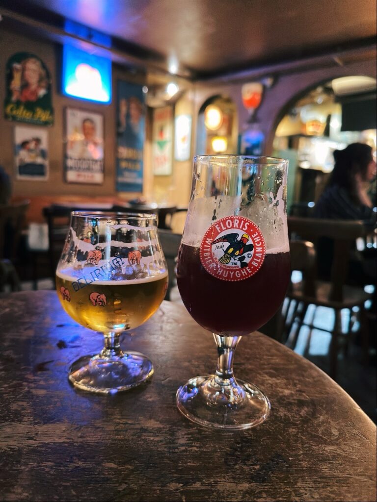 Two glasses of beer sit on a wooden table in a Brussels bar