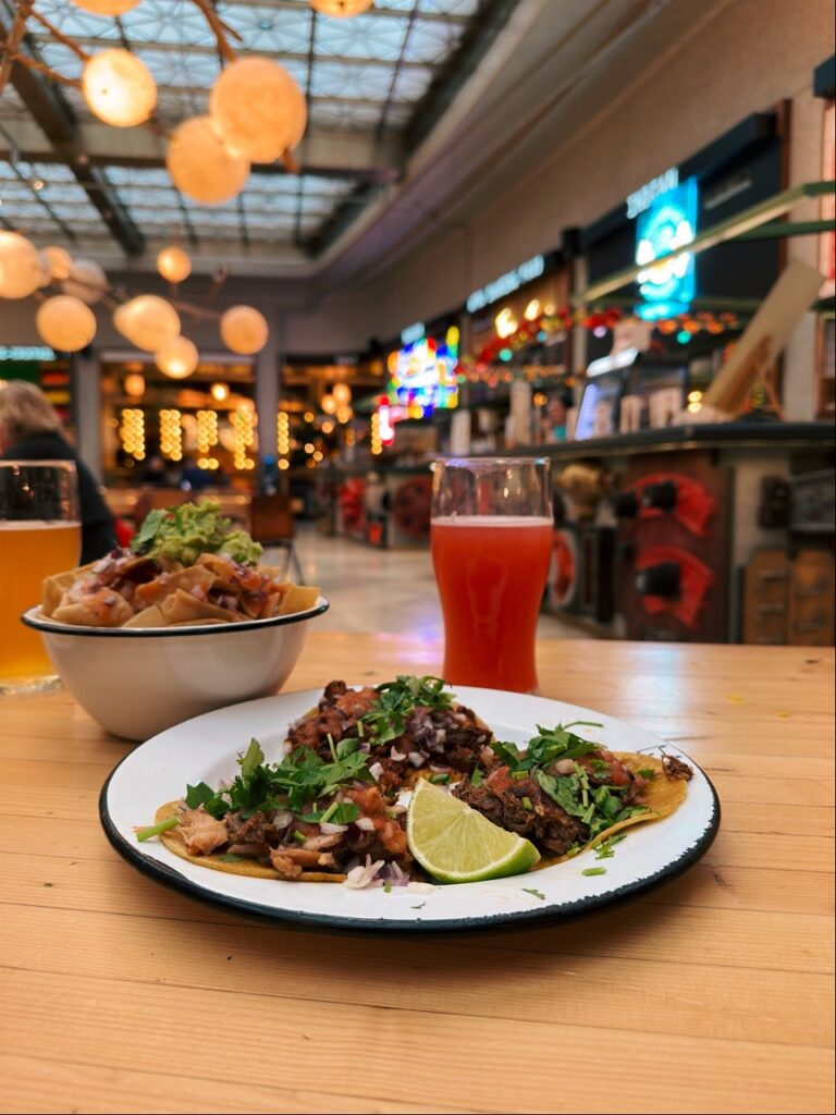 Tacos with lime and cilantro served on a plate next to a glass of red drink in Brussels restaurants