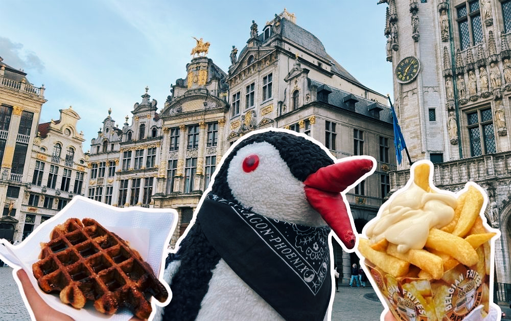 Penguin Miško poses with a waffle and cone of Belgian fries in front of historic Brussels buildings