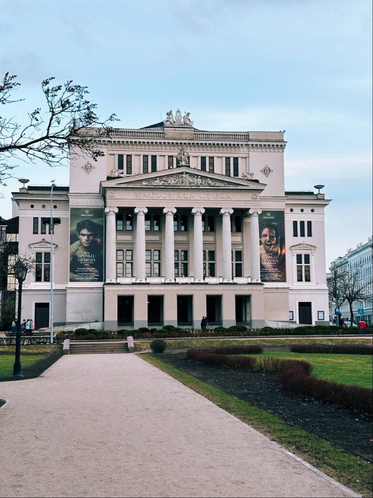 Elegant historic palace facade with columns and molding, bearing the sign DŽUNGĻU GRAMATA NAC NALA OPERA ZINGL GAMATA