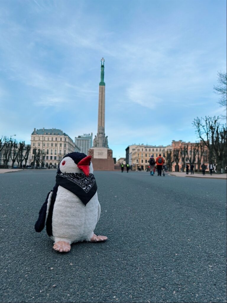 A plush penguin toy standing among a crowd of people in a snowy street