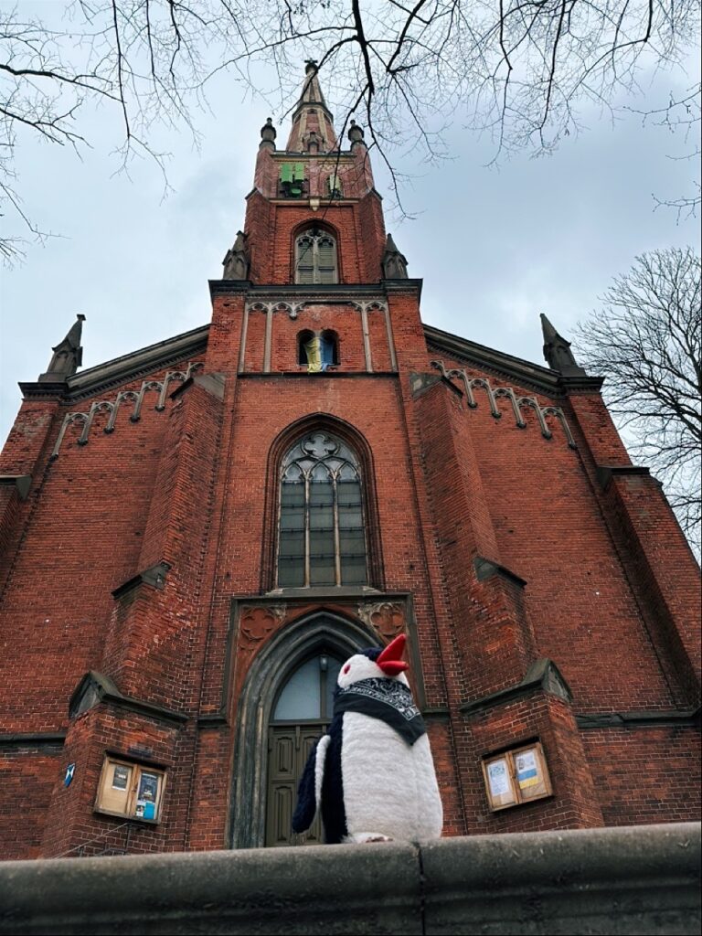 Tall church spire with steep roof and pointed steeple against a cloudy sky